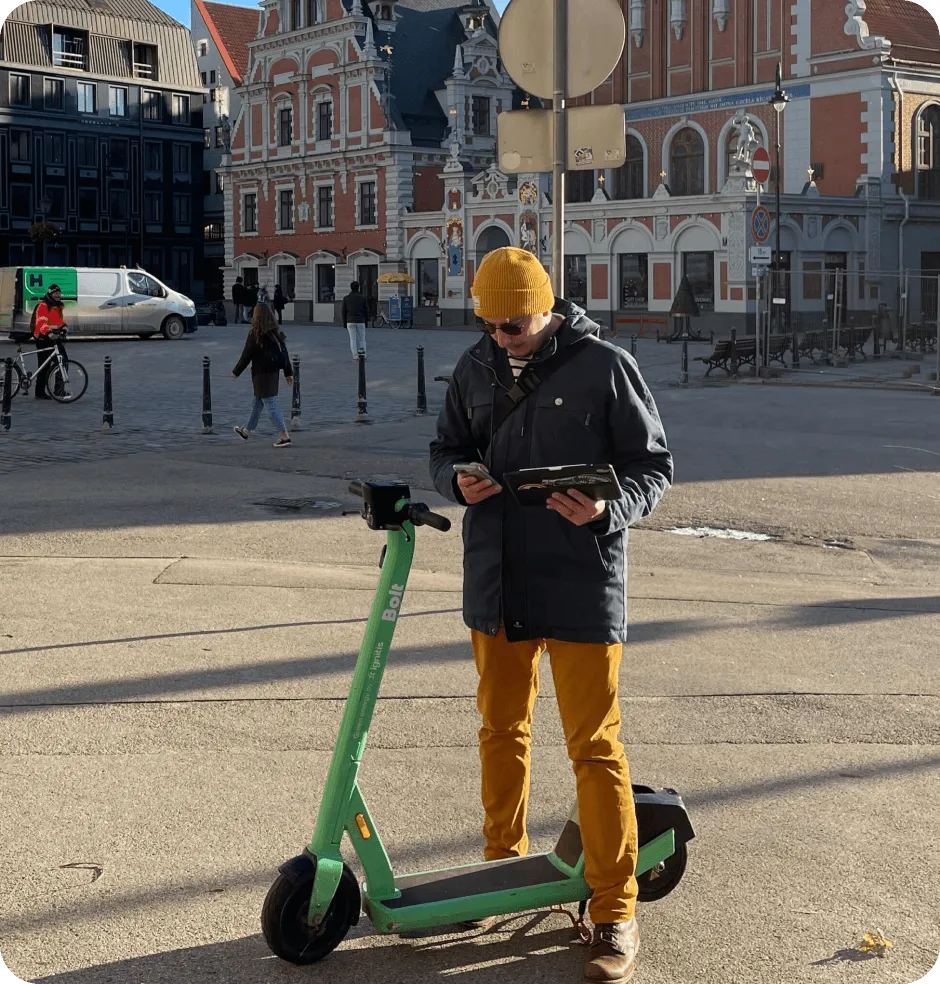 A man standing next to a green scooter.